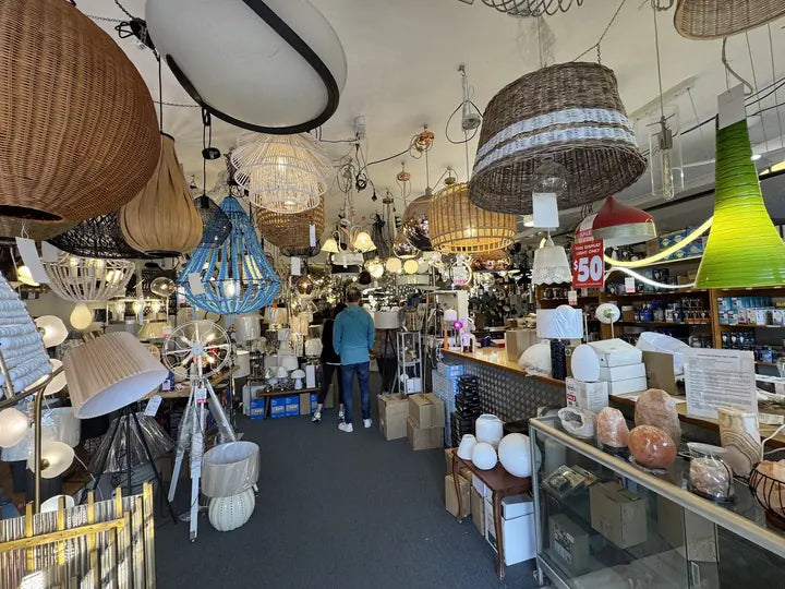 Table lamps lit on the shelves under rattan pendants in the Cosmo Lighting showroom